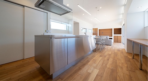 フローリングの茶系、壁面の白系が映り込むことで、建具とキッチンをつなぐ自然なグラデーションが生まれます。