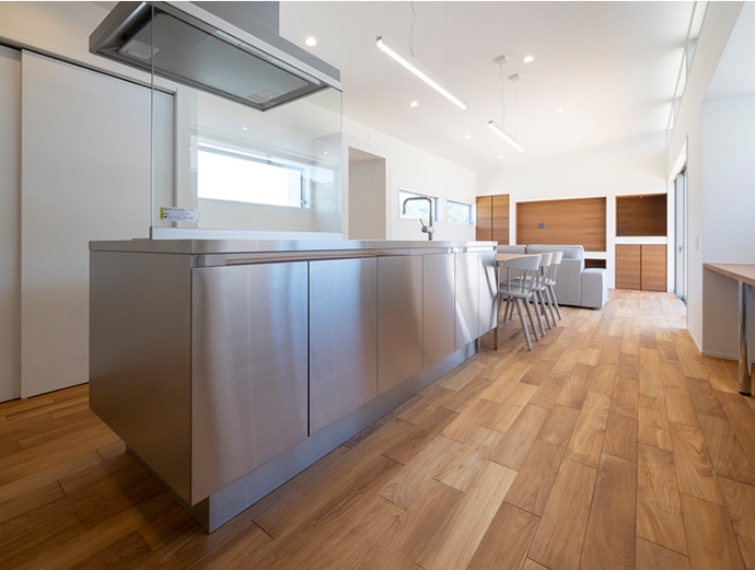 フローリングの茶系、壁面の白系が映り込むことで、建具とキッチンをつなぐ自然なグラデーションが生まれます。