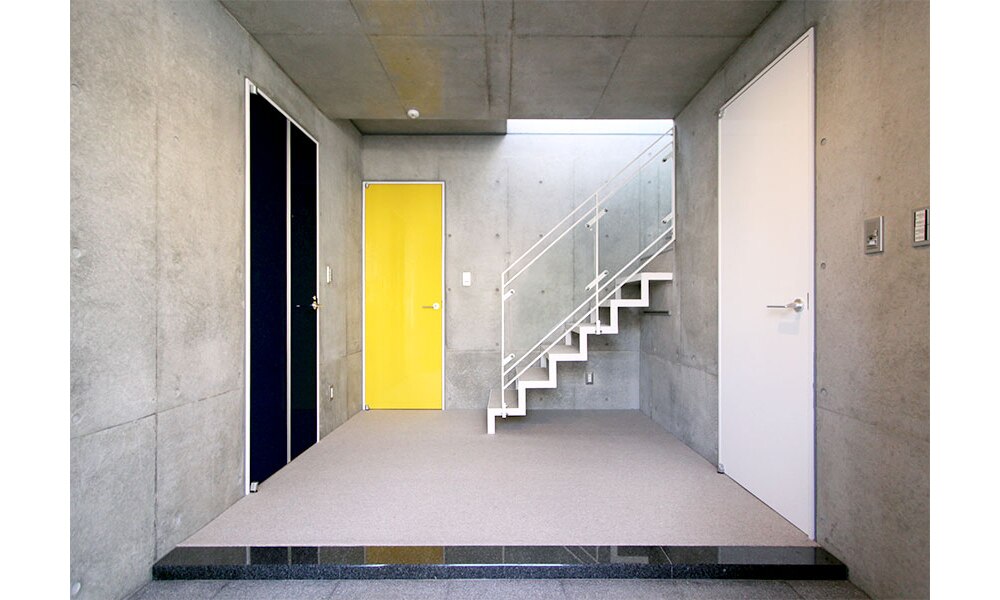 打ちっぱなしの壁にビビッドな扉のアクセント