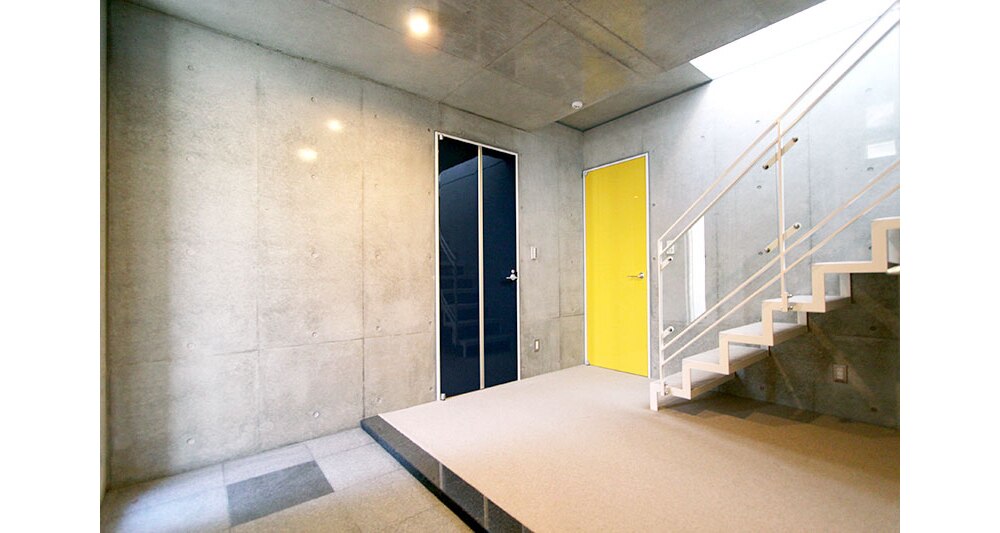 打ちっぱなしの壁にビビッドな扉のアクセント