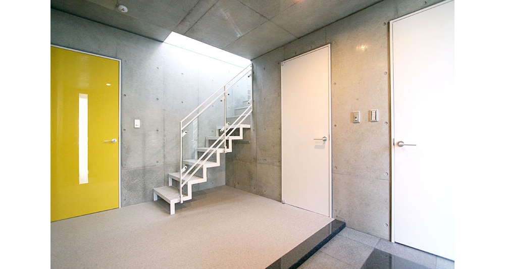 打ちっぱなしの壁にビビッドな扉のアクセント