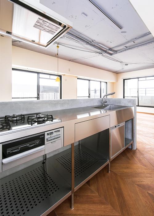 インダストリアルなステンレスの質感に馴染むモルタルの造作キッチン