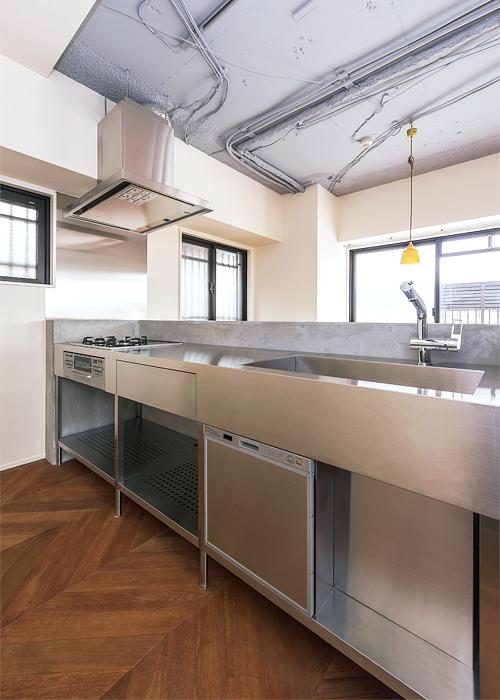 インダストリアルなステンレスの質感に馴染むモルタルの造作キッチン