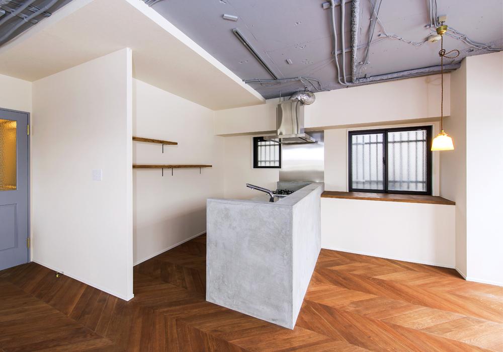 インダストリアルなステンレスの質感に馴染むモルタルの造作キッチン