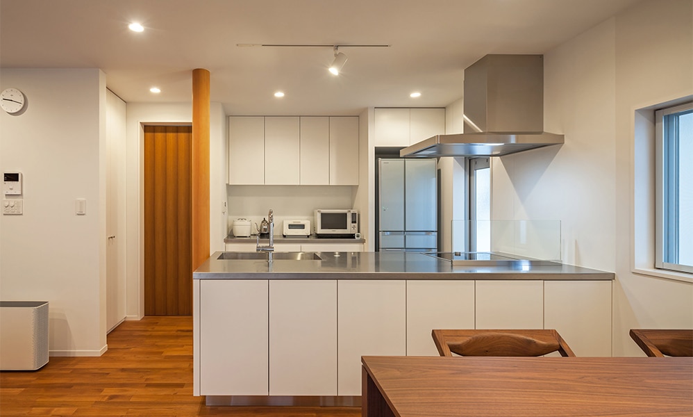 チークのフローリングが味わい深いシステムキッチンとカップボードの事例