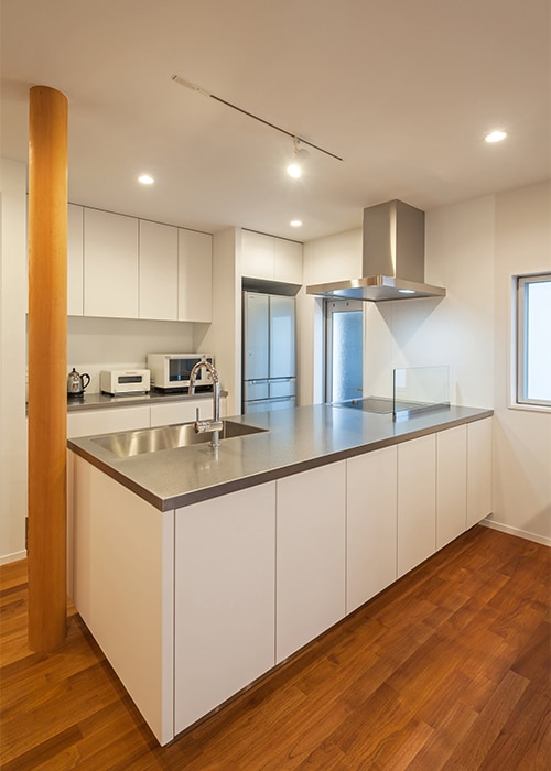 チークのフローリングが味わい深いシステムキッチンとカップボードの事例