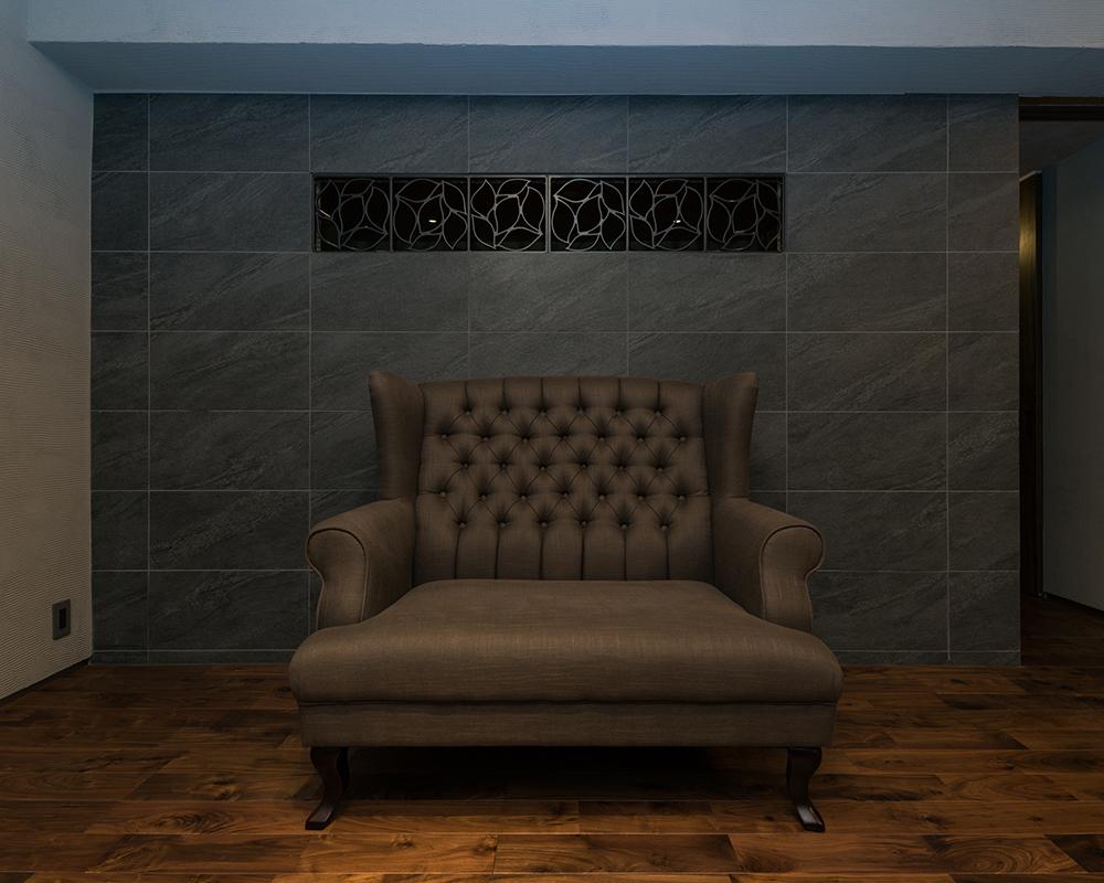 アイアン飾りを埋め込んだ黒ストーン壁のリビング