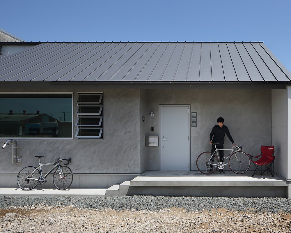 モルタル仕上げの外壁と自転車専用の玄関ポーチ