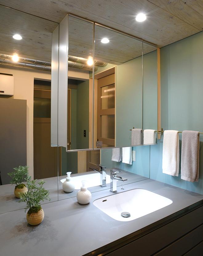 洗面台のグレーと壁のグリーンで淡く柔らかい印象の洗面スペース