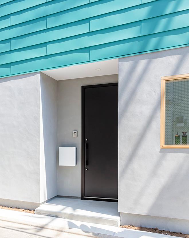 鮮やなターコイズブルーの外壁と、モノトーンの組み合わせが爽やかなエクステリア