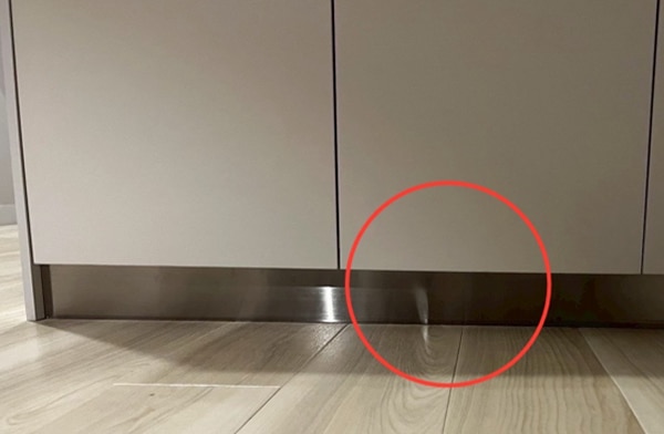 本体の足元の巾木の ステンレスが変形し歪んでいる様子