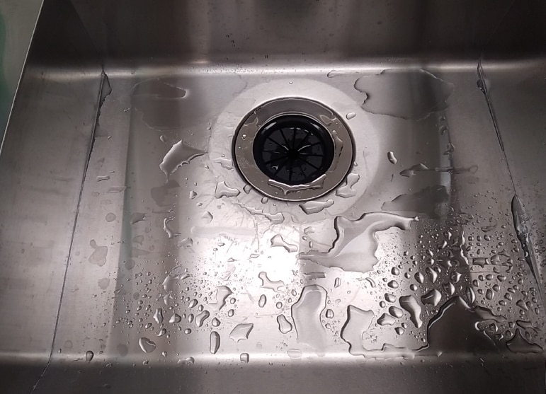 キッチンシンクの底面に流れ切らない水が残る様子